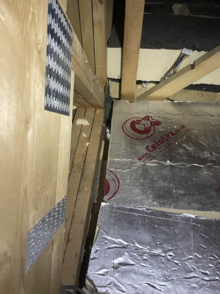 Looking down on loft insulation with large gaps between insulation and timber frame.